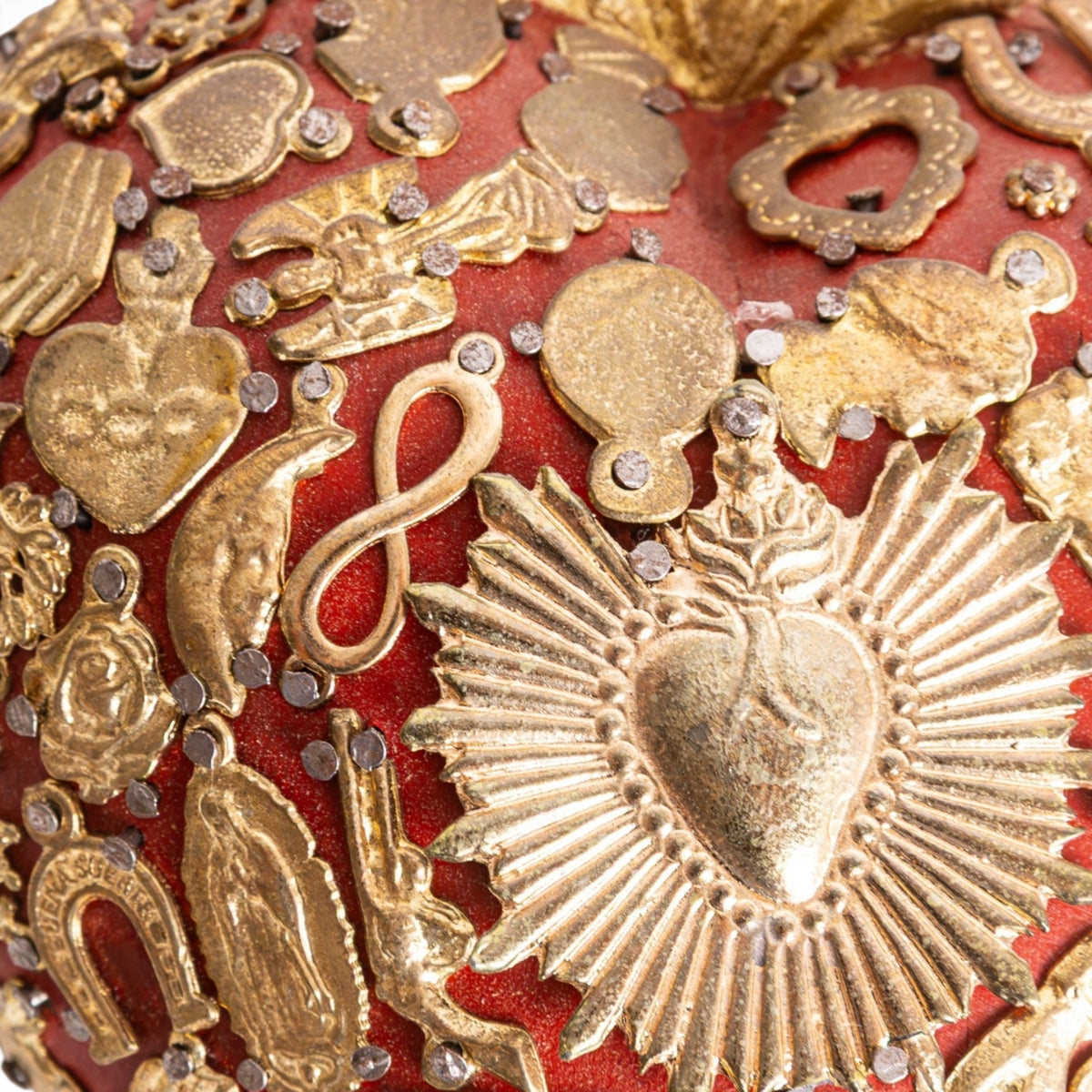Détail des médailles en métal sur ex-voto sacré-cœur rouge artisanal
